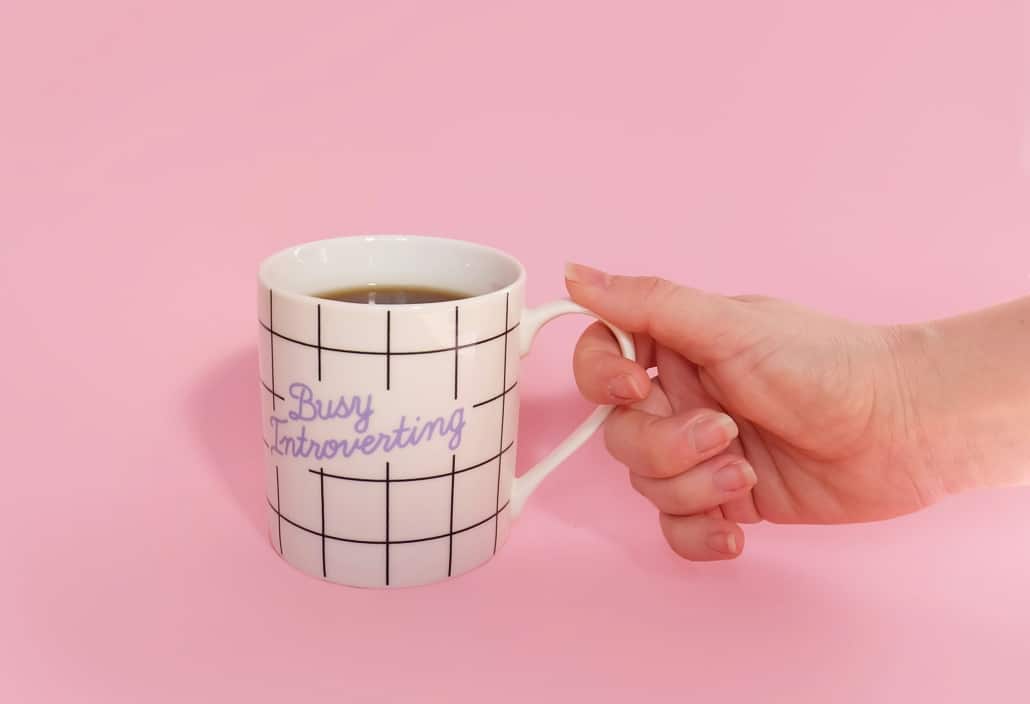 Image of mug for introverts against a pink background captioned busy introverting