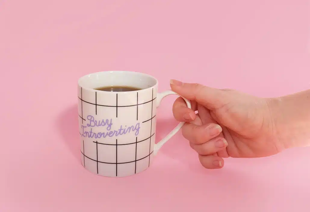 Image of mug for introverts against a pink background captioned busy introverting